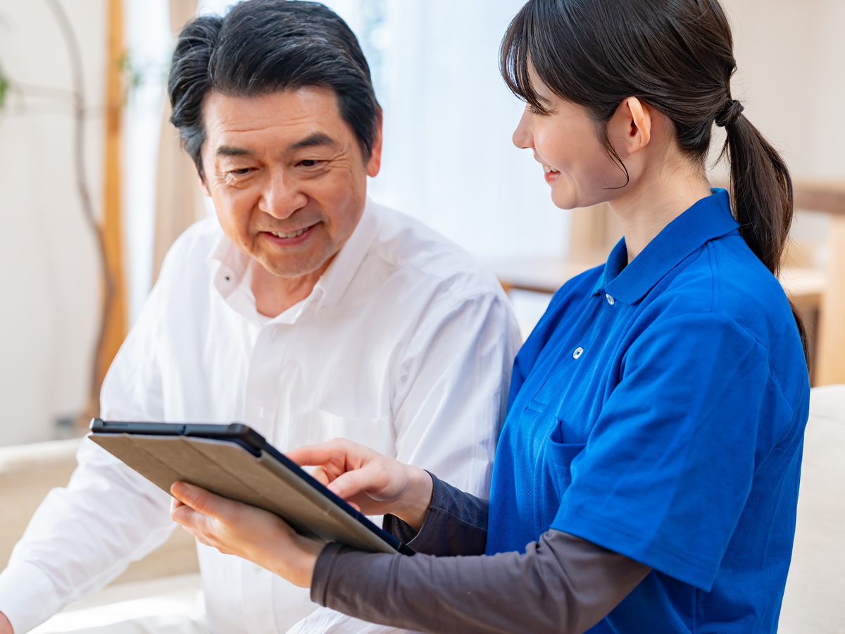 高齢男性にタブレットで説明するスタッフ