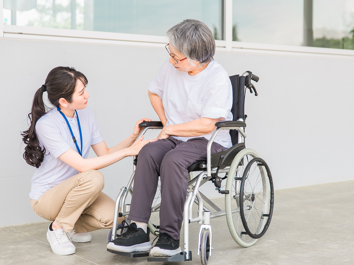 車いすの高齢者を支援する介護スタッフ